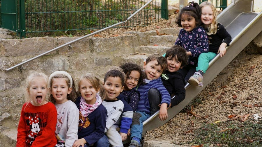 FitScouts Kindergarten: Kindergartengruppe lacht gemeinsam auf einer Natursteintreppe