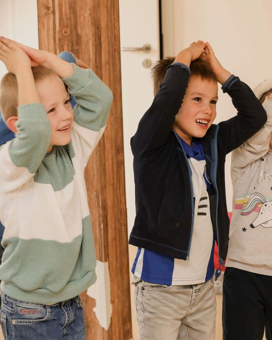 FitClass Grundschulbetreuung Wiesbaden: Grundschulkinder strecken beim Bewegungsspiel die Arme nach oben