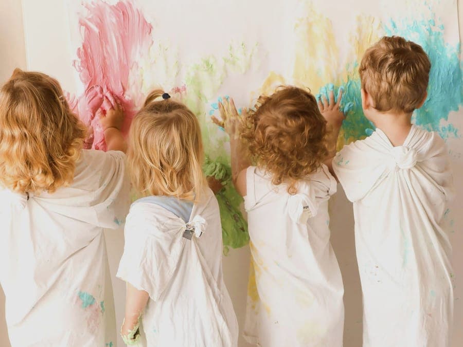 Fit for Family Care Kindergarten: Kinder malen gemeinsam an einer großen Leinwand