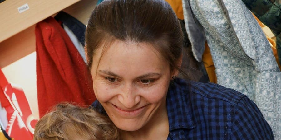Erzieherin hält ein Kind geborgen auf dem Schoß in der FFF-Kita Wiesbaden