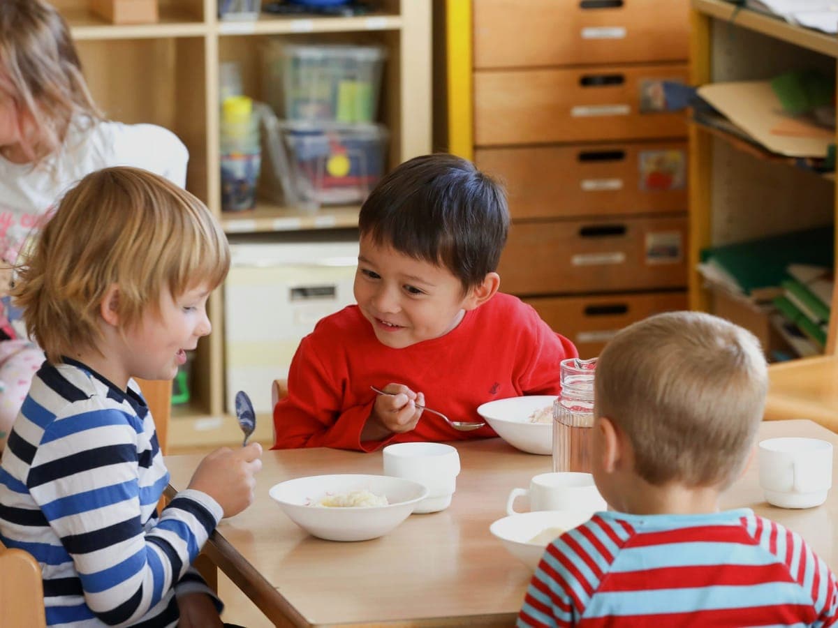 Kinder essen gemeinsam am Mittagstisch in der Kita