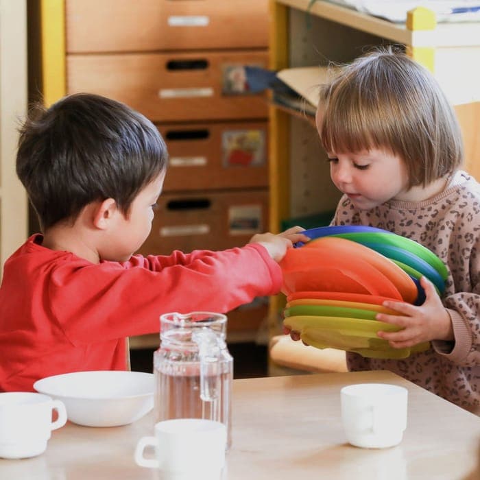 Kinder decken gemeinsam den Tisch in einer Einrichtung von Fit For Family Care